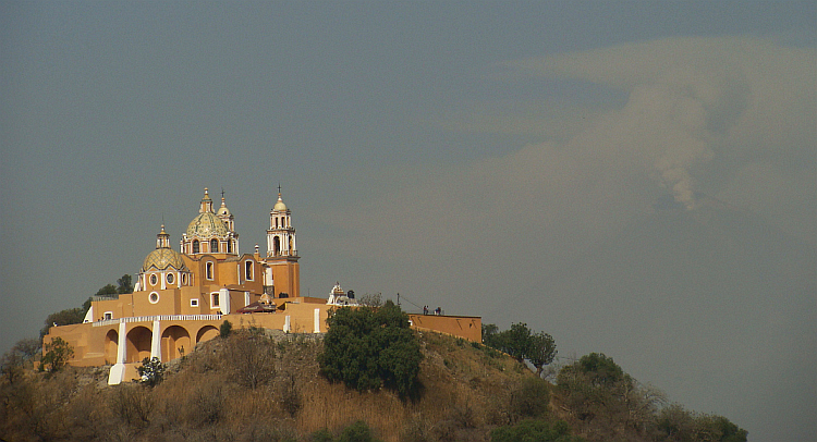 Church of Cholula with the volcano Popocatépetl veiled in ash clouds